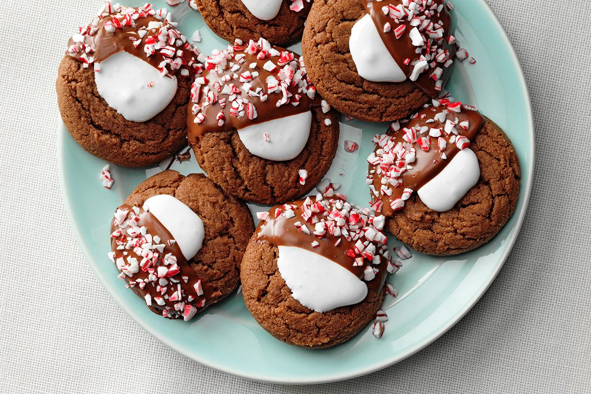 A plate of chocolate cookies topped with melted chocolate, marshmallow, and crushed peppermint candy, arranged on a light blue plate.