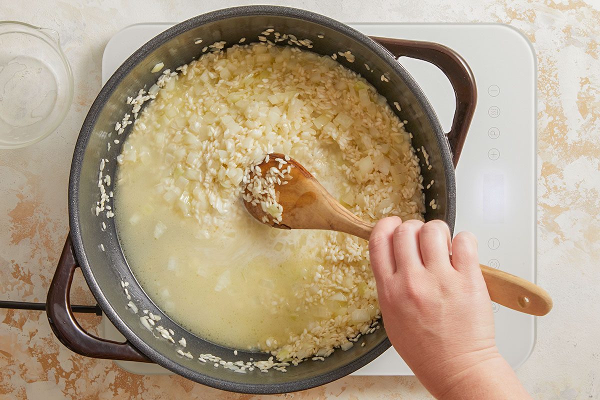 Overhead shot of risotto simmering as broth is gradually added, showing a creamy texture forming.