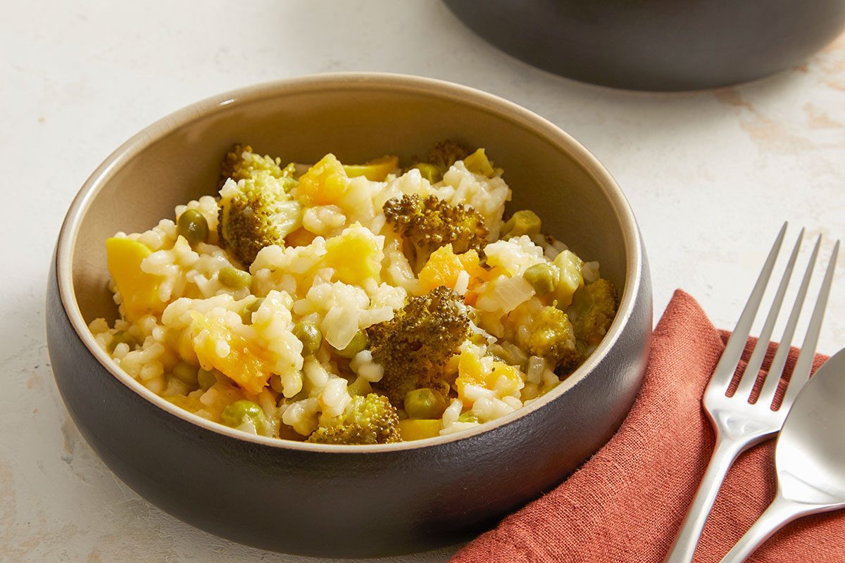 Overhead shot of a serving of Vegetable Risotto in a brown bowl with a fork placed beside it.