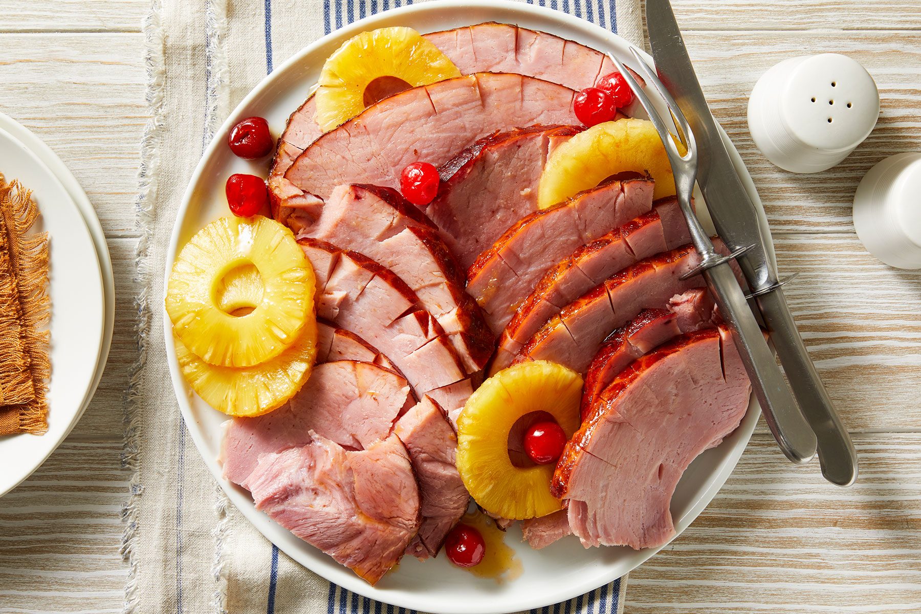 Baked Ham With Pineapple cut into pieces and served on a plate with salt and pepper shaker placed on side.