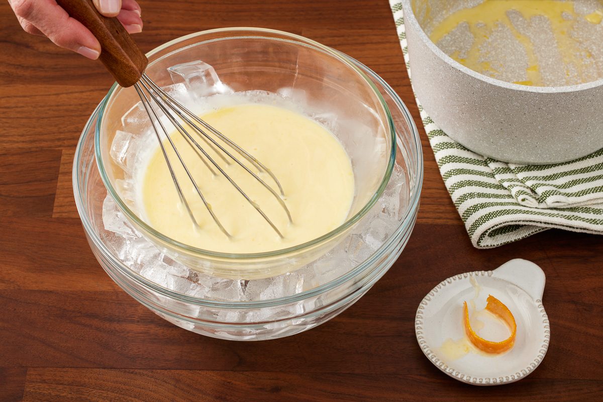 bowl with custard sauce in ice-water bath being stirred with a whisker