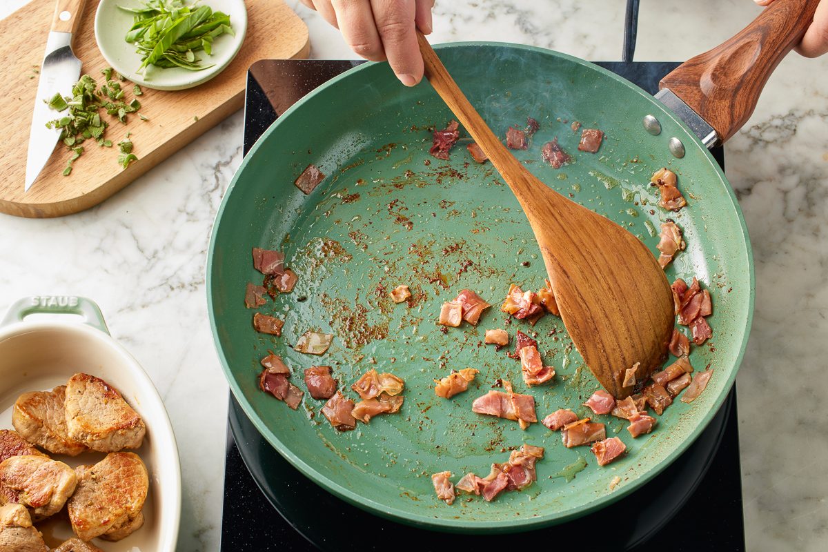 chopped prosciutto being sautéed in a pan